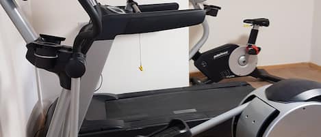 Una bicicleta estática con pantalla digital y una cinta de correr.