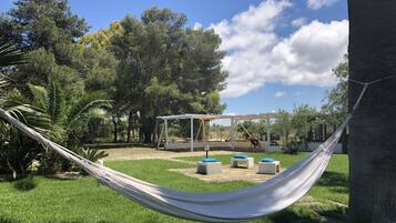 Una hamaca en un espacio verde con una pérgola y mobiliario de exterior.