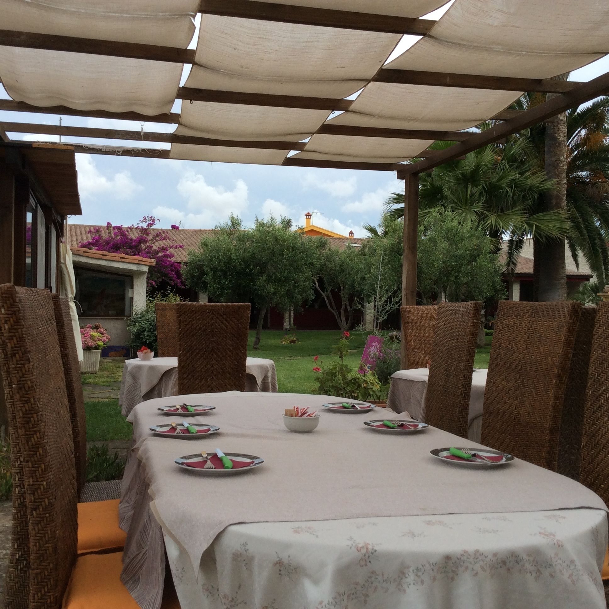 An outdoor dining area with a covered patio, wicker chairs, and a table set for four.