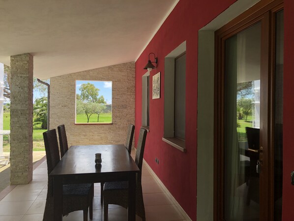 A dining area with a table and chairs, a window with a view of trees, and a red wall.