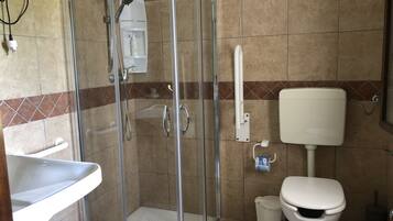 A bathroom with a glass-enclosed shower, a white toilet, and a sink.