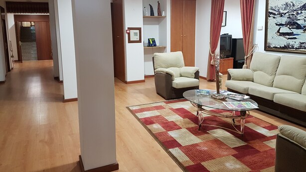 Una sala de estar con sofá, sillones, una mesa de centro y televisión.
