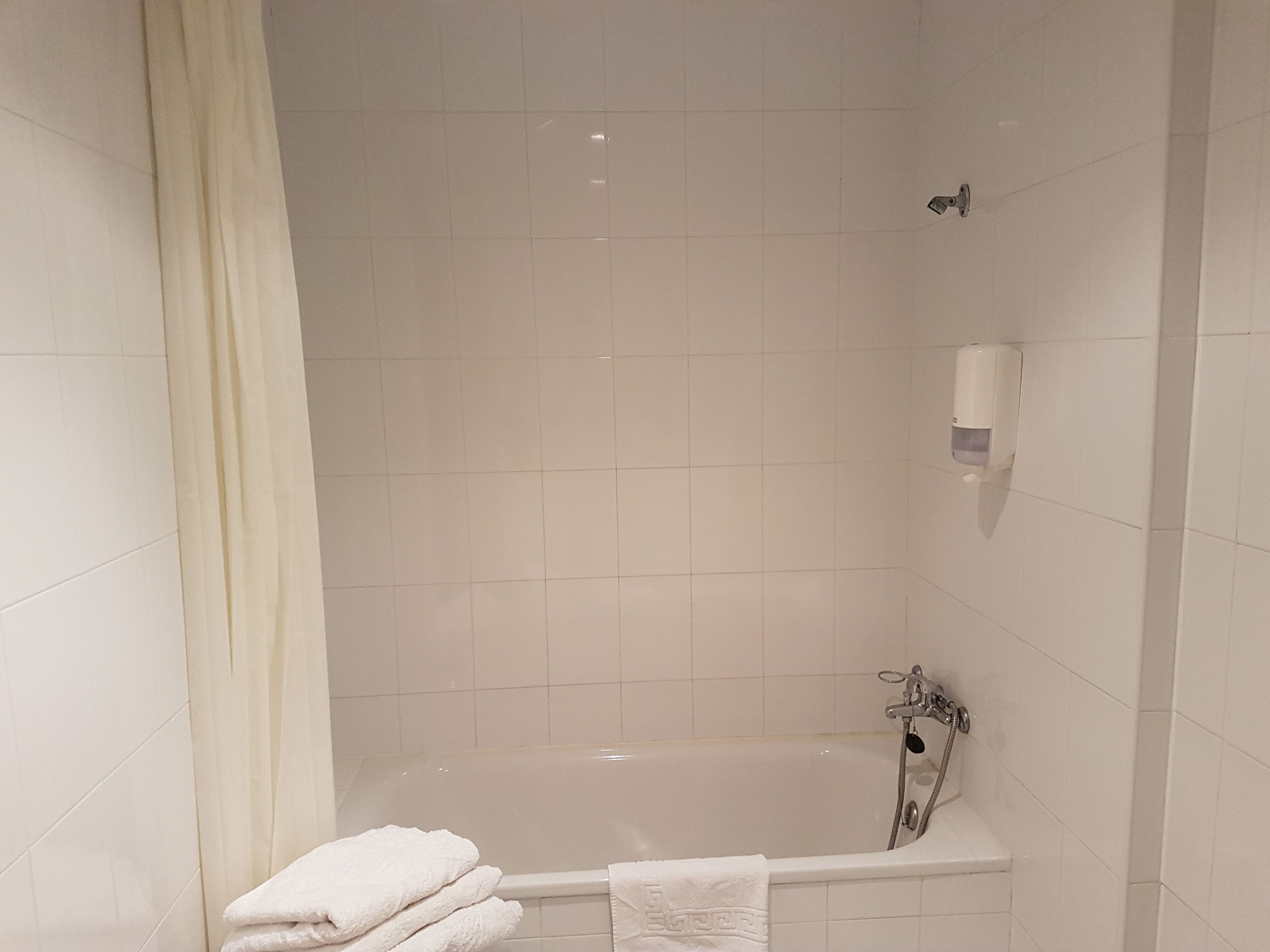 Une salle de bain équipée d’une baignoire, d’un distributeur de savon liquide et d’un porte-serviettes.