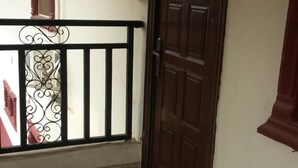 A room with a tiled floor, a wooden door, and a balcony with a metal railing. - Kings Crown Hotel (Lagos)