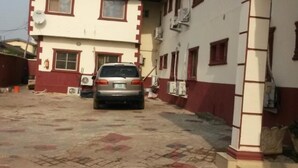 A building with a car parked in front. - Kings Crown Hotel (Lagos)