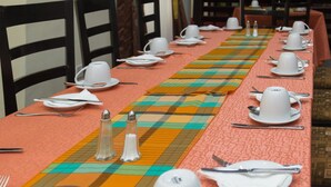 A dining table set with white dishes, silverware, and a colorful table runner. - Kings Crown Hotel (Lagos)