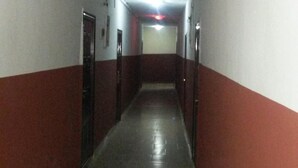 A long, narrow hallway with red and white walls, a tiled floor, and doors on both sides. - Kings Crown Hotel (Lagos)