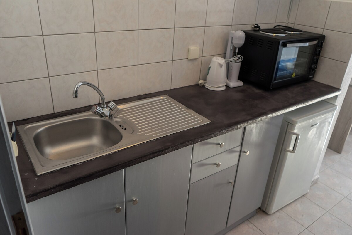 Una cocina con un lavamanos de acero inoxidable, un microondas y una cafetera.