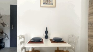 Una mesa de comedor con dos sillas, un cuadro en la pared y una botella de vino.