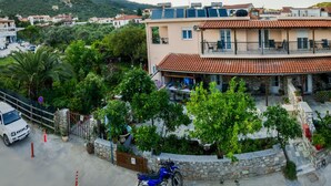 Un edificio de varios pisos con terraza, asientos exteriores y un jardín.