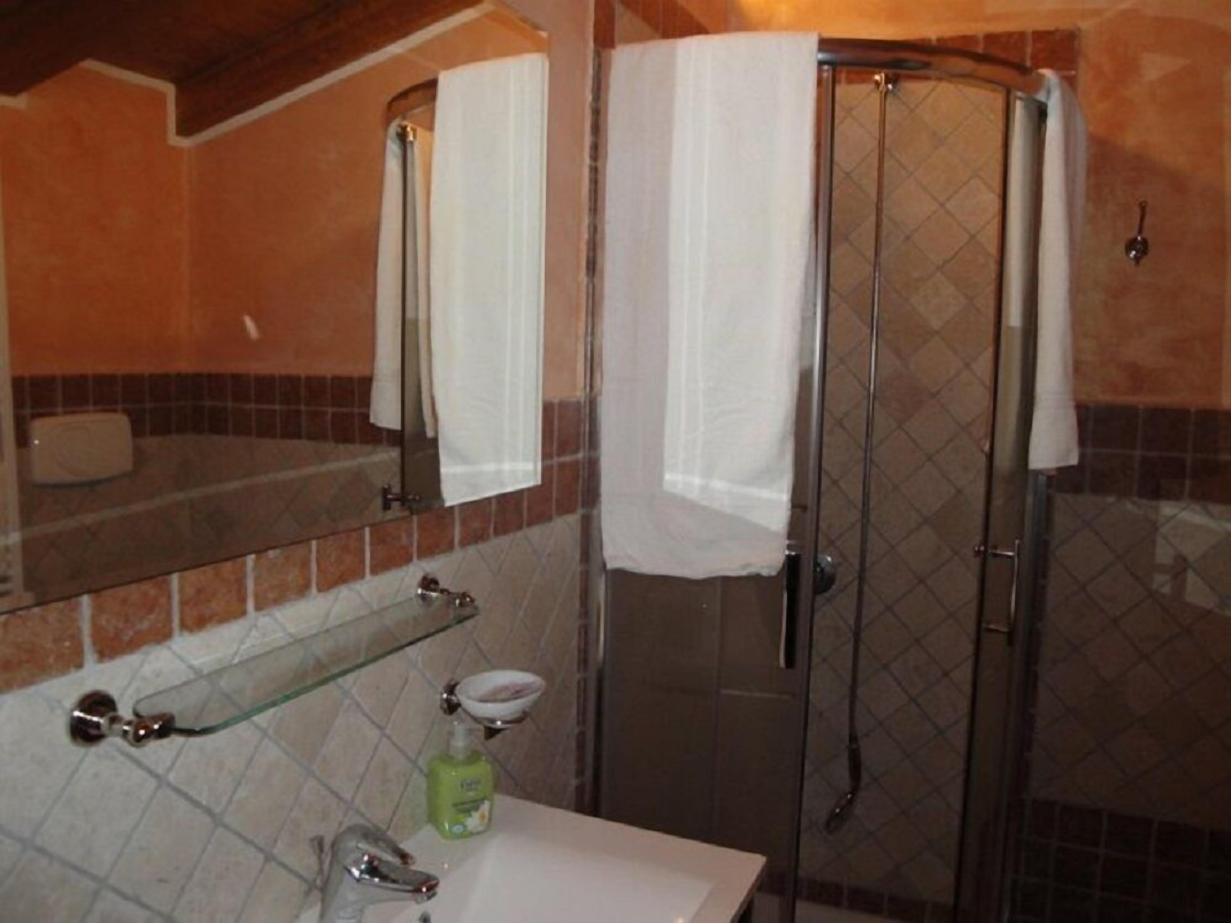 A bathroom with a glass-enclosed shower, a white sink, and a mirror above the sink.