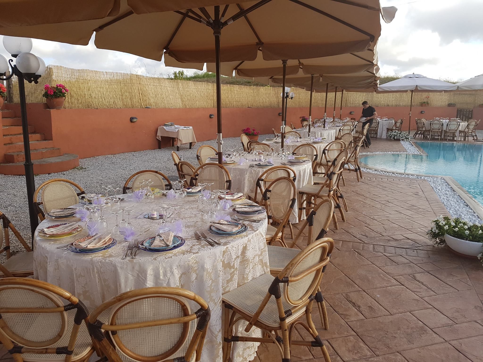 Een buitenterras met ronde tafels, rieten stoelen en parasols.