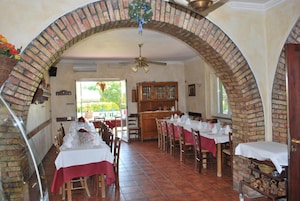A restaurant with brick arches, wooden tables, and a view of greenery outside.