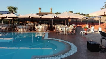Een zwembadgedeelte met tafels en stoelen, omringd door parasols en zonnecollectoren.