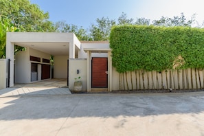 A modern house with a garage, a wooden door, and a neatly trimmed hedge.