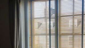 A bedroom with a bed, a window with blinds, a radiator, and a curtain. - Auplands (Lymington)