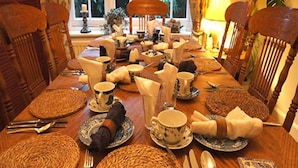 A dining table set with various dishes, utensils, and woven placemats. - Auplands (Lymington)