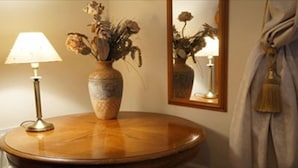 A round wooden table with a vase of dried flowers and a lamp. - Auplands (Lymington)