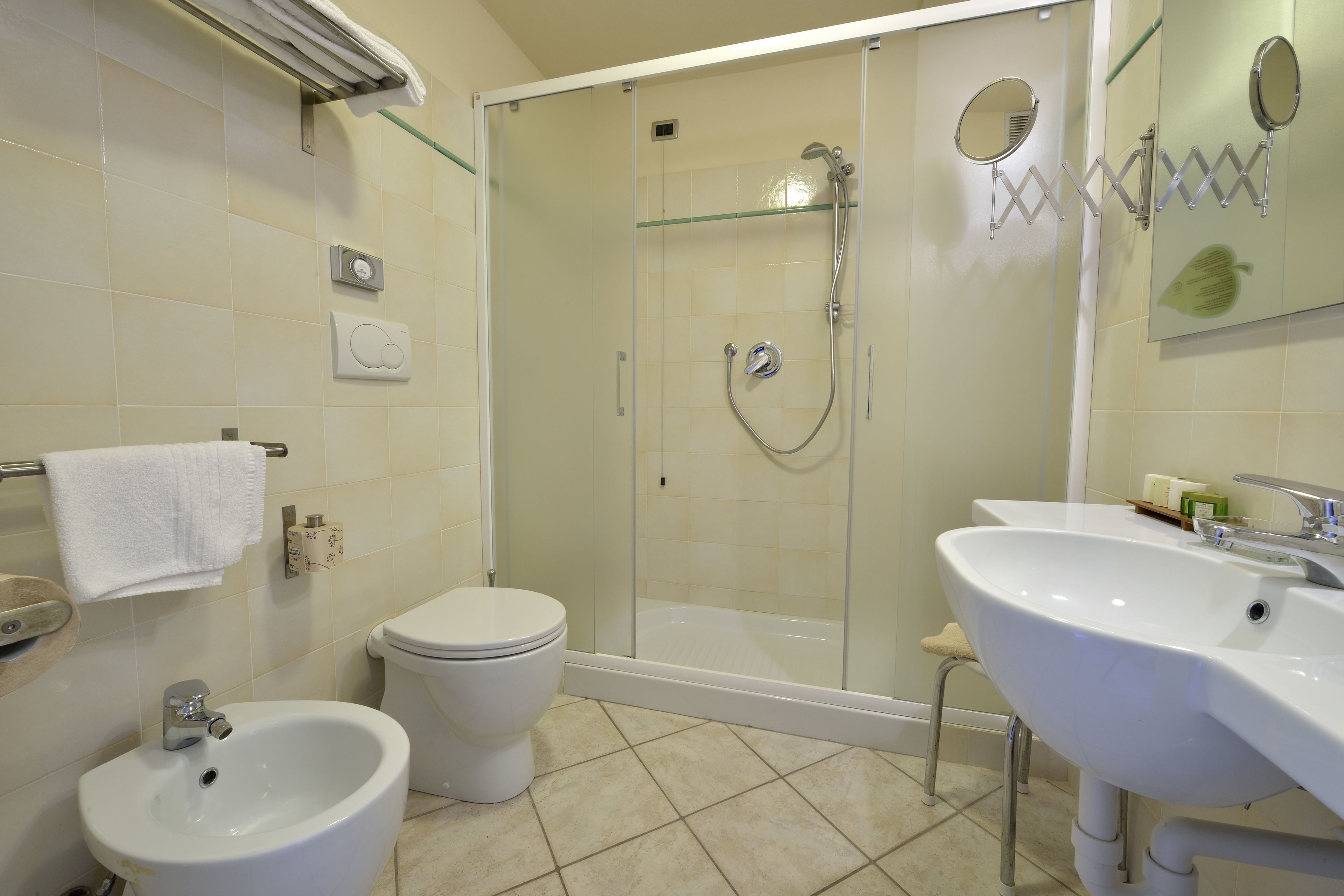 Un ba ño con ducha de mampara de vidrio, un bidé, un inodoro y dos lavamanos.
