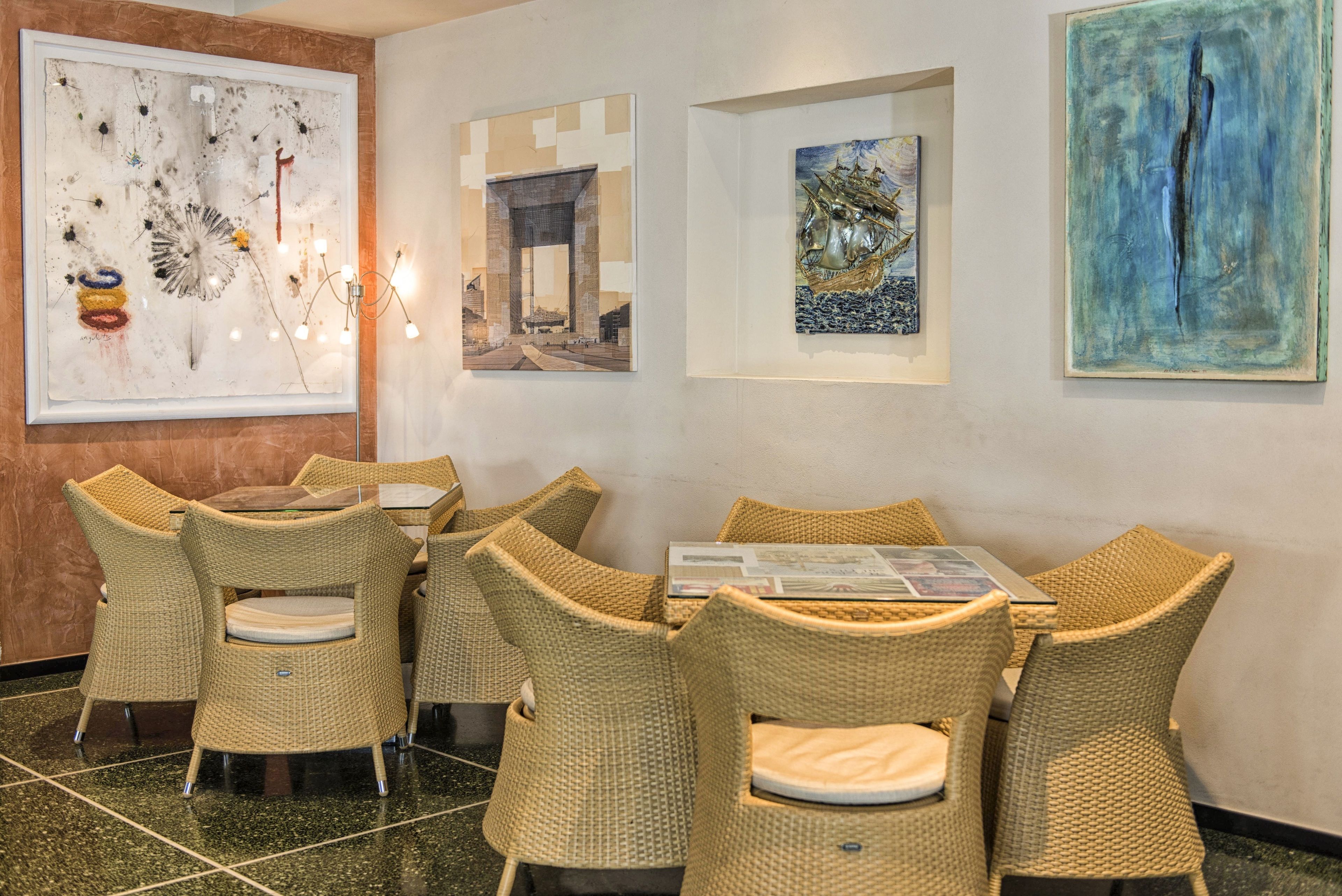 A dining area with wicker chairs and a table, surrounded by artwork on the walls.