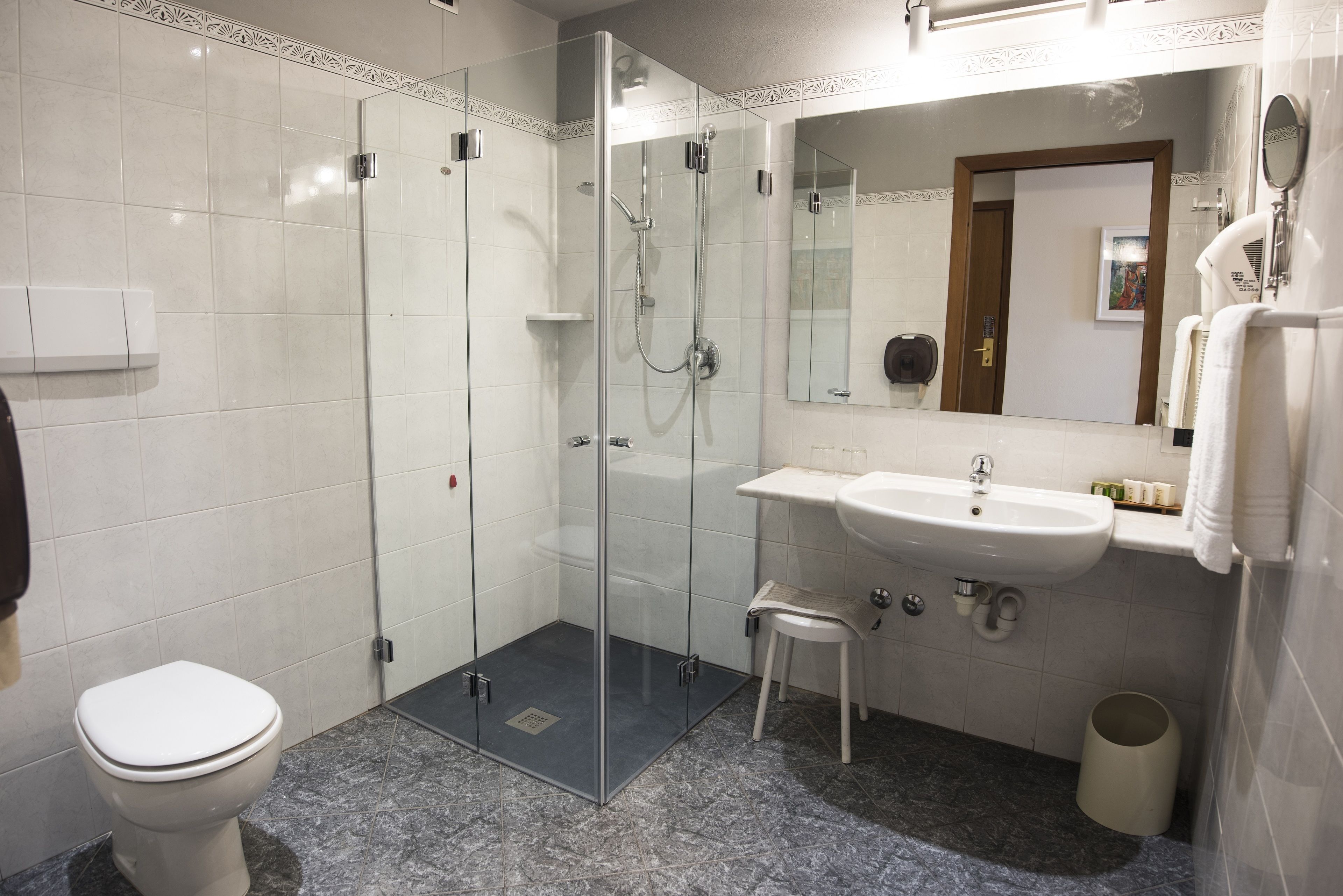 Ein modernes Badezimmer mit einer gläsernen Dusche, einem weißen Waschbecken und einer Toilette.