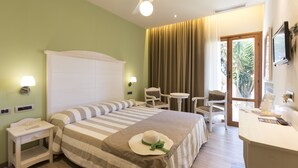 A hotel room with a large bed, a desk, a chair, a small table, a TV, and a window with curtains. - Hotel Liliana Diano Marina (Diano Marina)