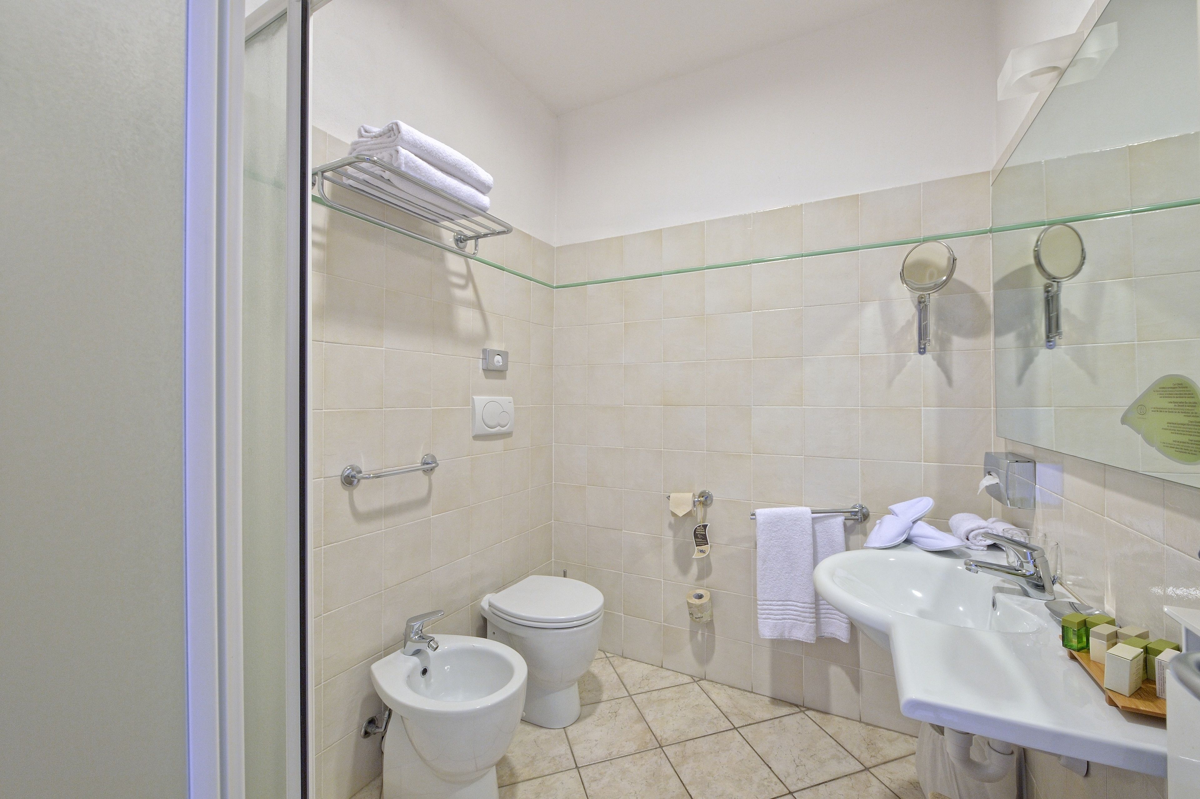 A bathroom with a toilet, bidet, sink, and glass shower enclosure.