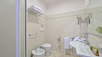 A bathroom with a toilet, bidet, sink, and glass shower enclosure.