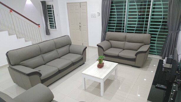 A modern living room with two grey sofas, a white coffee table, and a small potted plant.