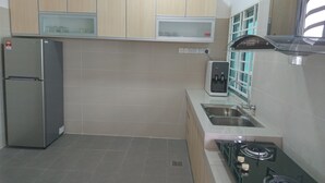A modern kitchen with a stainless steel refrigerator, a microwave, a water dispenser, and a gas stove.