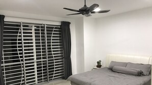 A bedroom with a bed, a ceiling fan, a window with blinds, and a nightstand with a plant.