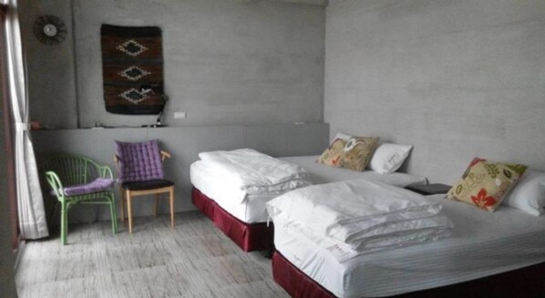 A room with two beds, a chair, and a wall-mounted decorative item.