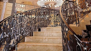 Una majestuosa escalera con barandales de metal ornamentados y una serie de luces colgantes.