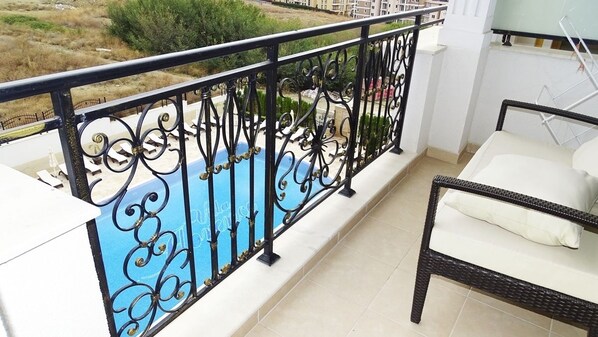 A balcony with a black wrought iron railing, a white sofa, and a view of a green landscape. - Villa Florence (Sveti Vlas)