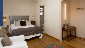 Un dormitorio con cama, mesita de noche, lámpara y una pequeña mesa con una vela.