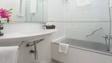 A bathroom with a white sink, a bathtub, and a mirror.