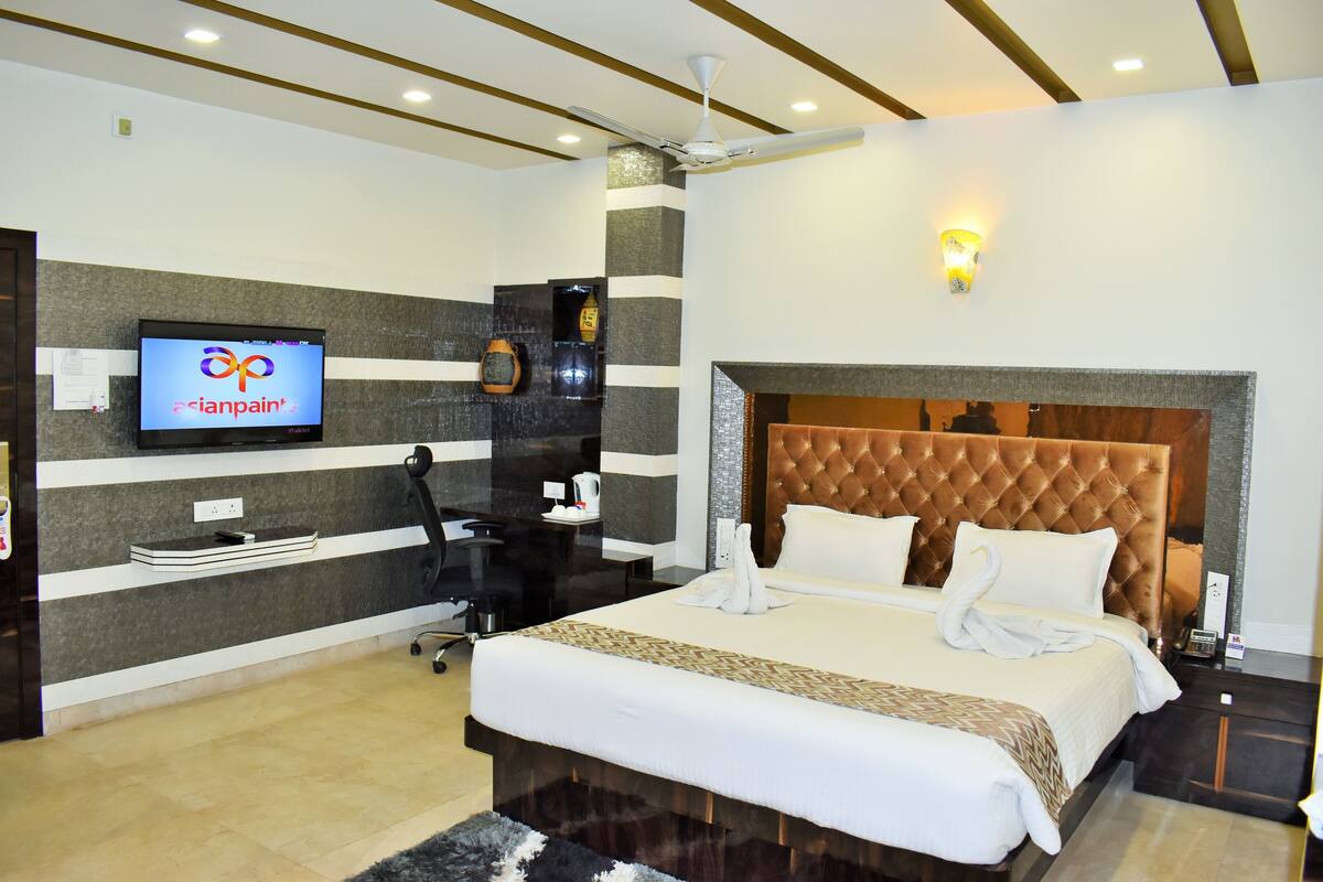 Una habitación de hotel moderna con una cama grande, un televisor de pantalla plana, un escritorio y una zona de estar confortable.