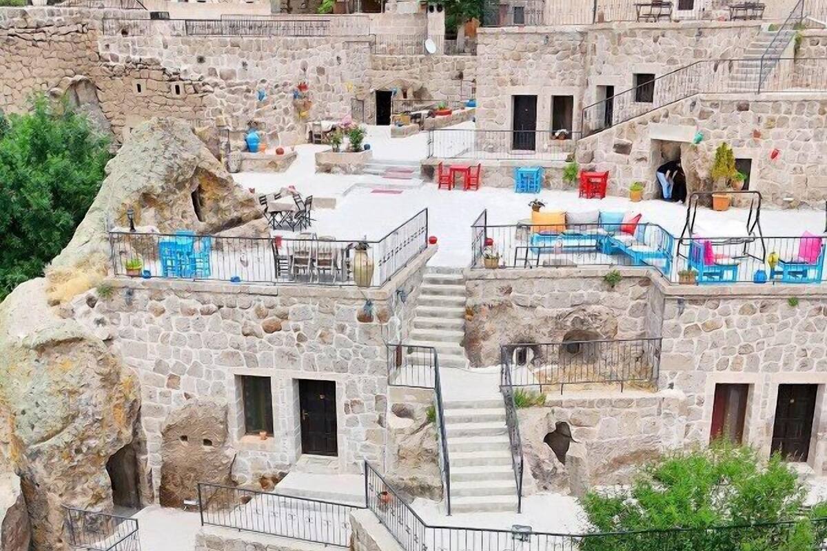 A stone building with multiple balconies, outdoor seating areas, and a central staircase.