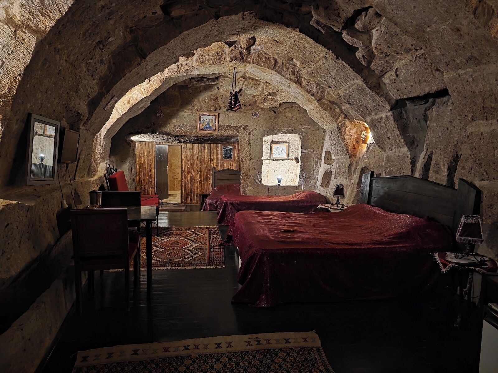 Ein rustikaler Raum mit Steinsandsteinwänden, einem Bett, einem Schreibtisch und einem Stuhl.