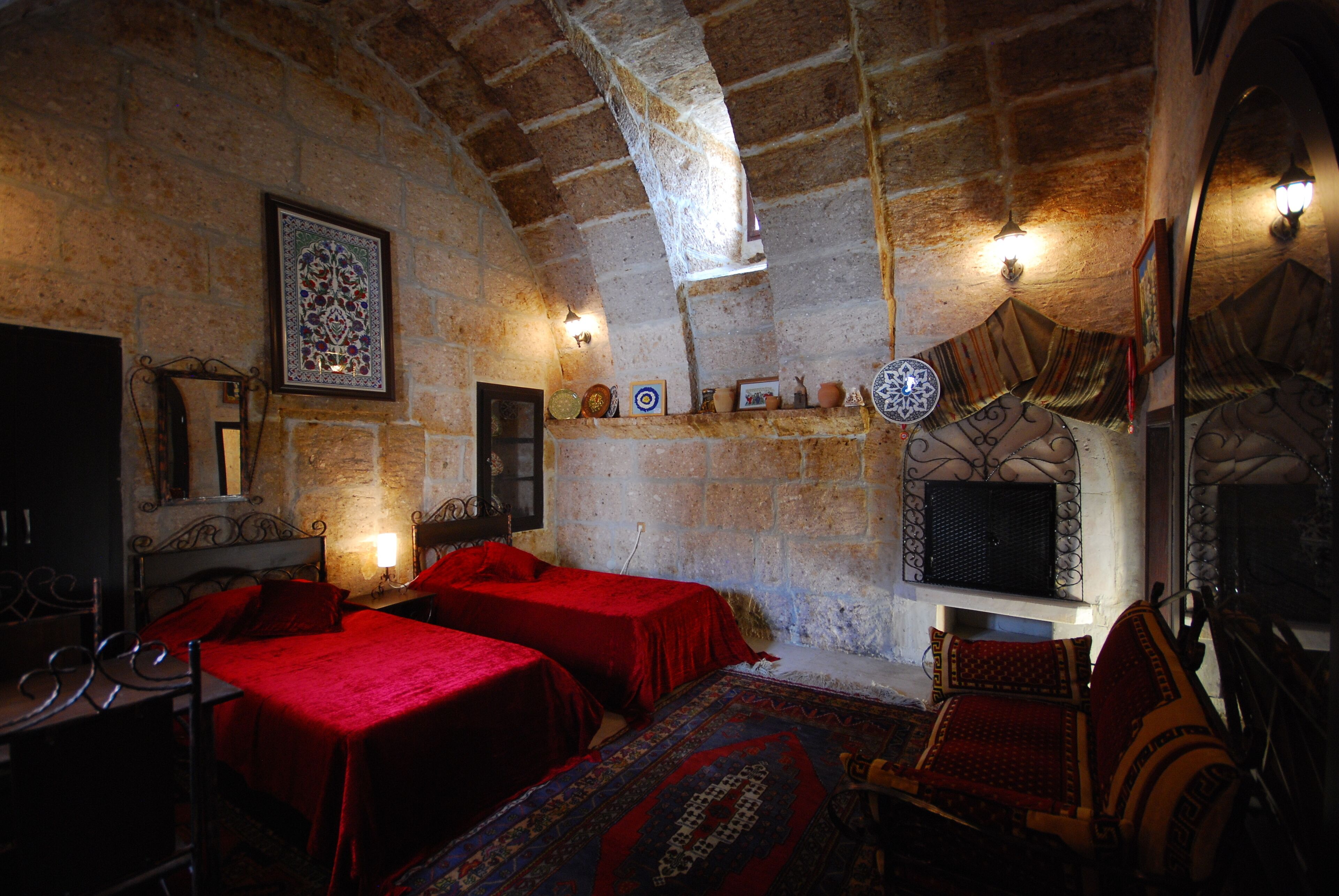 A traditional room with two beds, a fireplace, and stone walls.