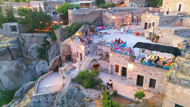 Un patio con edificios de piedra, mobiliario exterior y un espacio central abierto.