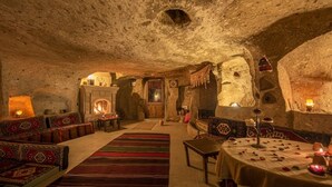 Un interior que recuerda a una cueva, con chimenea, zona de estar y una mesa dispuesta para una comida.