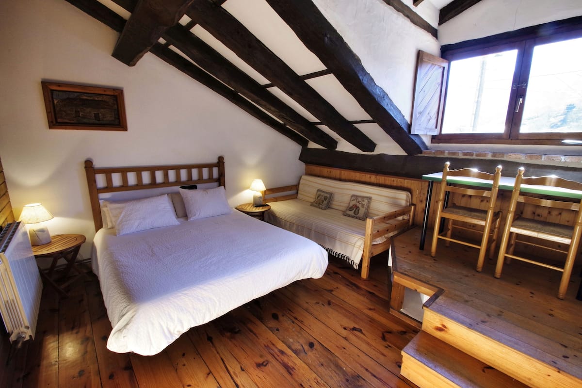 Un dormitorio acogedor con una cama de madera, un banco y un ventanal con vistas.