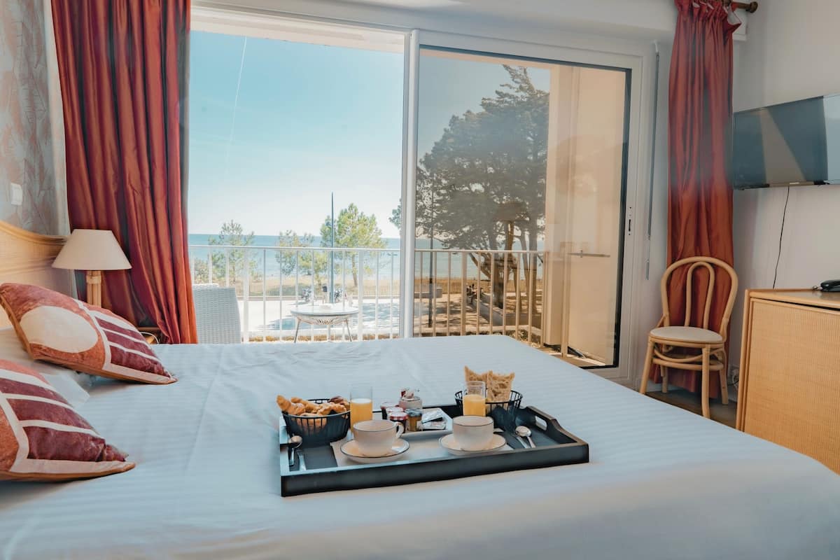 A hotel room with a bed, breakfast tray, and a balcony with a view.