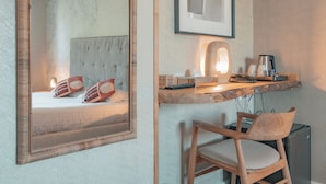 A bedroom with a bed, a bedside table with a lamp, a chair, and a desk with a computer. - Hôtel Edenia (Carnac)