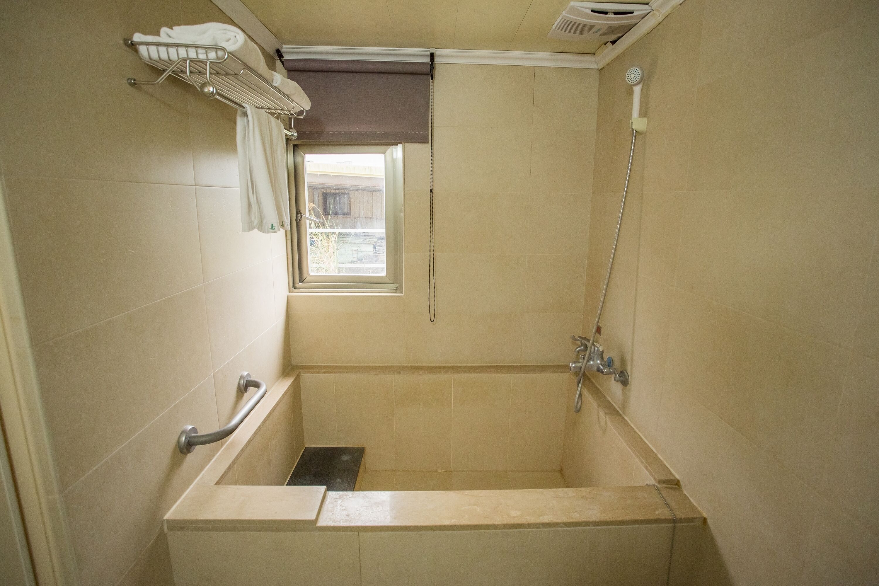 Un baño con bañera, ventana, toallero y ducha.
