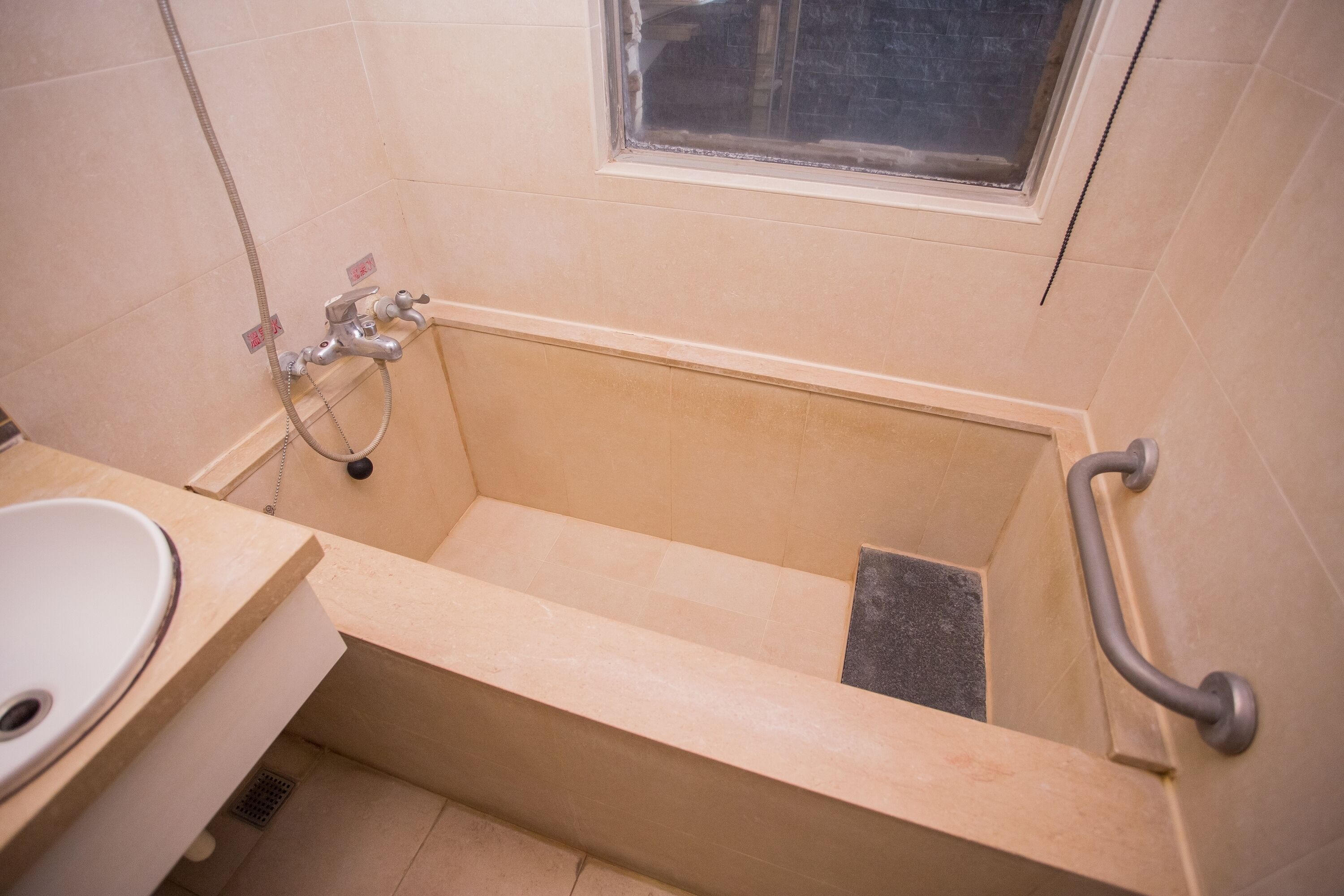 A bathroom with a bathtub, a sink, and a window.
