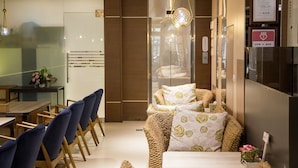 A modern hotel room with a wooden floor, a bed with patterned bedding, a dining area with blue chairs, and a visible emergency exit sign. - Mei Jia Mei Hotel (Jiaoxi)