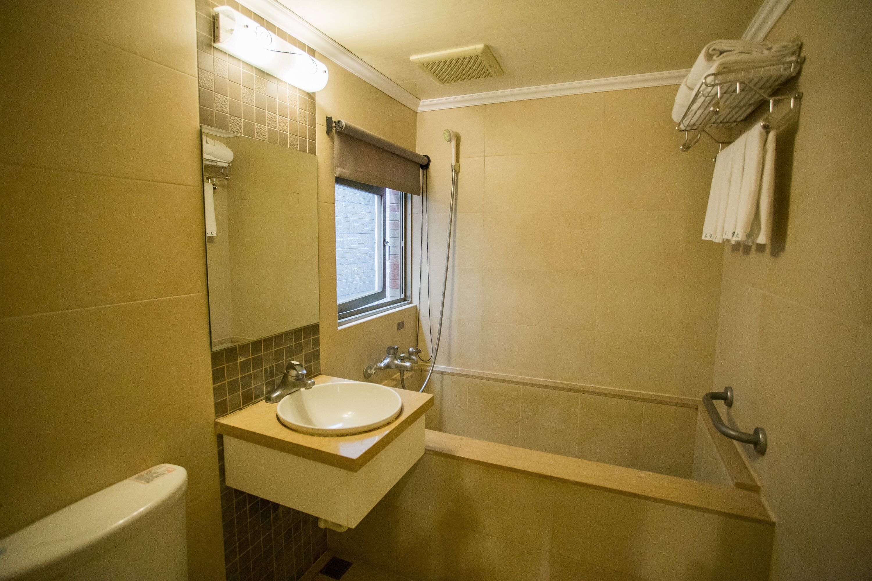 A bathroom with a sink, mirror, shower, and towel rack.