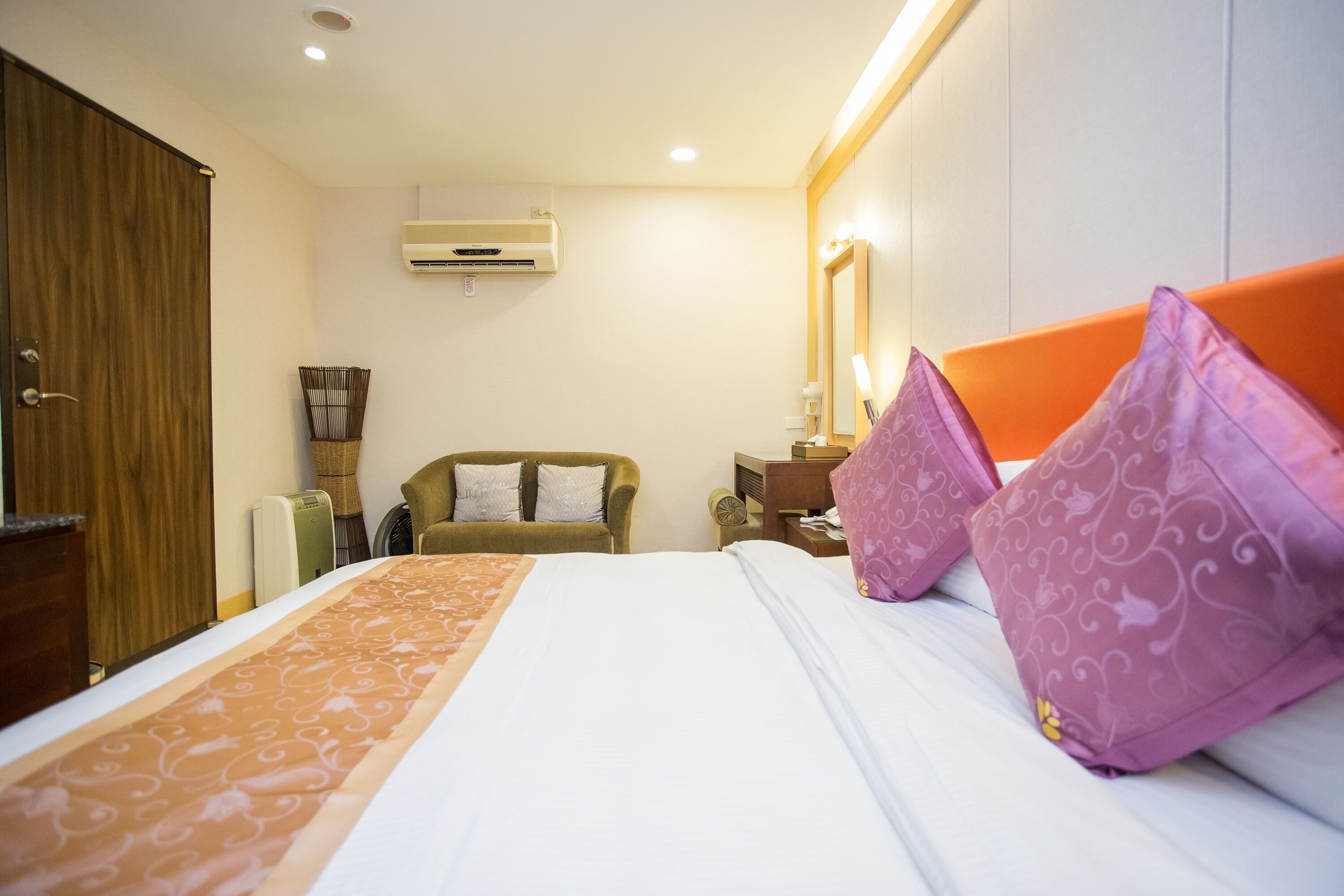 Une chambre d’hôtel comprenant un lit, une armoire, un canapé, un appareil de climatisation et un miroir.